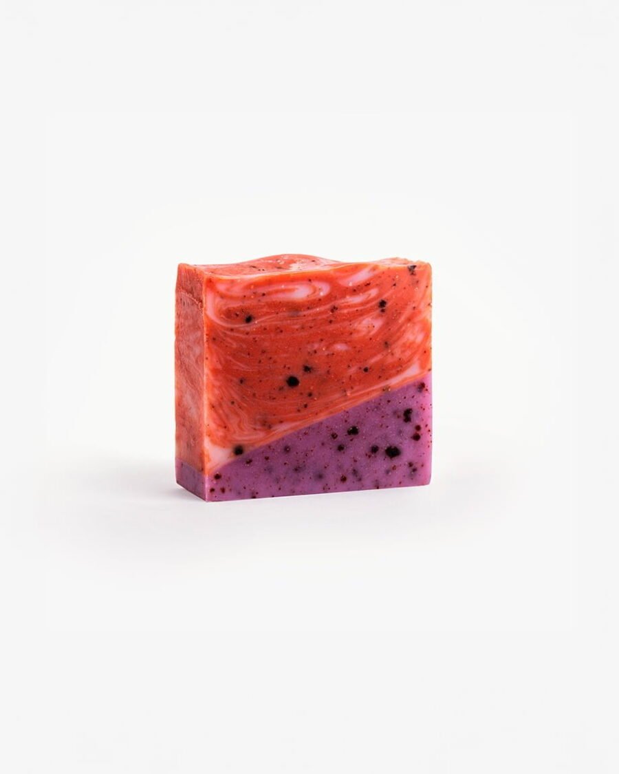 Handmade organic soap with swirls of crimson and purple, embedded with real cranberry and blueberry pieces for nourishing skincare.